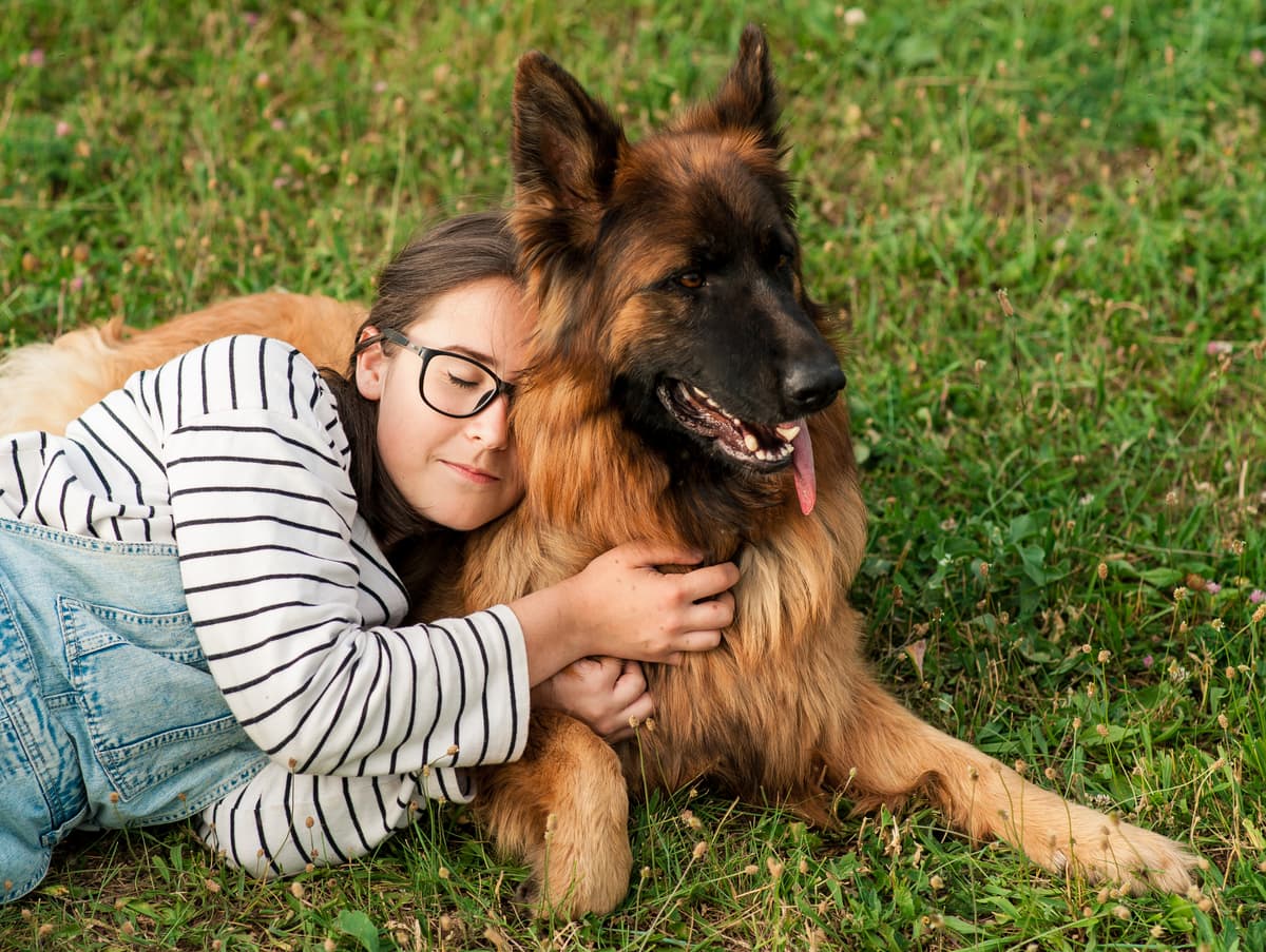 Girl hugging a German Shepherd in the grass